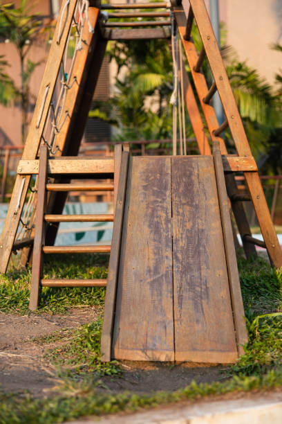 a playground in a tropical park with children's wooden slide and wooden stairs on the grass. evening light. - formal garden tropical climate park plant imagens e fotografias de stock