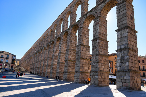 Segovia, Spain - January 25, 2024: People tourists sightseeing the impresive stone structure of the Roman Aqueduct.