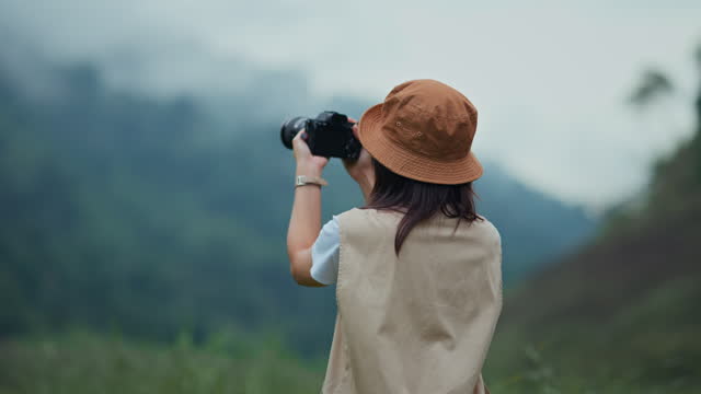 Happy young tourist female with camera taking photo of mountains and fog, Carefree woman in fields and stream, Rest on vacation holiday weekend