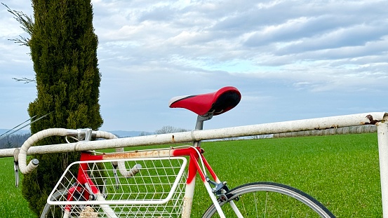 Rusty vintage red white racing bike lost at an old white railing rod