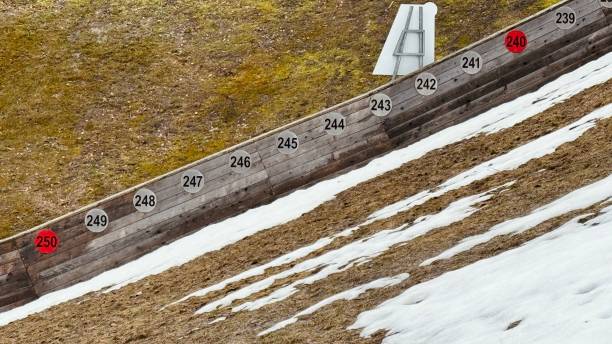 Teenage boy having freestyle ski training in public park on ski-jump at springtime