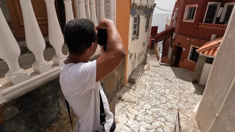 A man is taking a picture of a building. The building is old and has a lot of windows