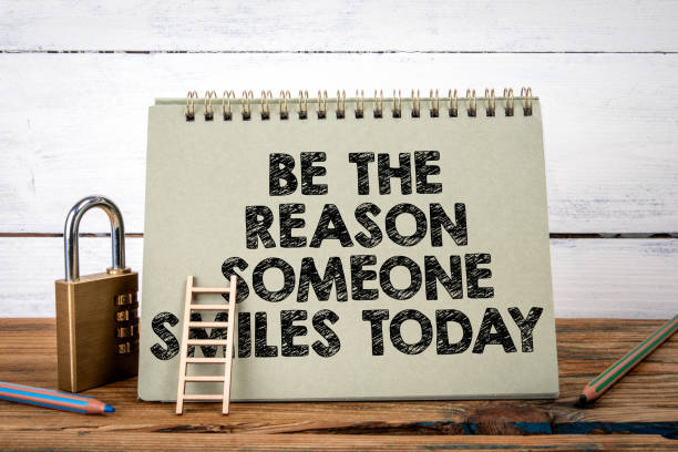 istock Be The Reason Someone Smiles Today. Green notepad on wooden texture table and white background 2094092122