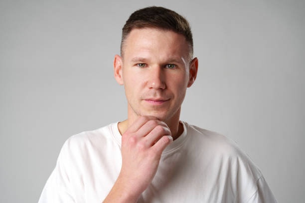 istock Thoughtful caucasian young male touching chin with hand thinking on gray background 2094097662