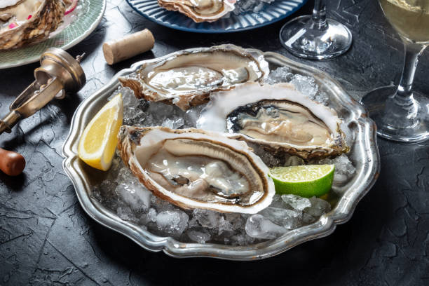 istock Oysters on ice at a restaurant, with lemon, lime, and white wine, on black 2094103433