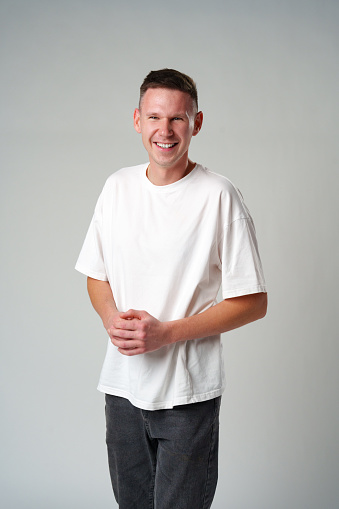 portrait of young smiling man wearing casual clothes on gray background in studio