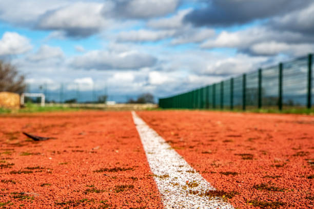 istock Red running track with white lines and blue sky in the background. 2094106621