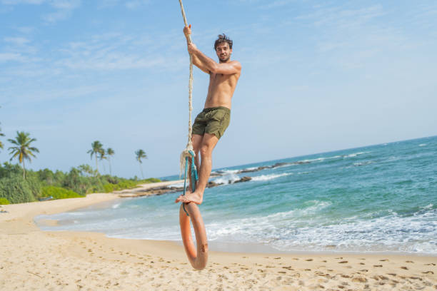 istock Young man swings over beach 2094126831