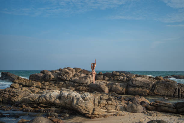 Young woman relaxes on rocky shoreline at dusk