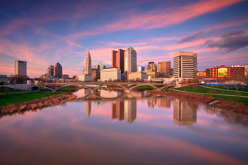 Cityscape image of Columbus , Ohio, USA downtown skyline with the reflection of the city in the Scioto River at spring sunset.