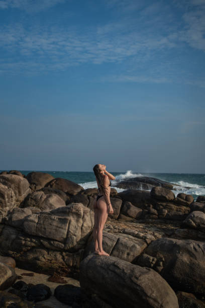 Young woman relaxes on rocky shoreline at dusk