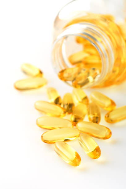 Close up capsules with Vitamin D, E or Omega 3,6,9 fatty acids in bottle top view isolated on white. Food supplement oil filled fish oil. Natural supplements for healthy good life concept. Banner.
