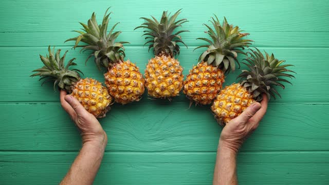 Stop motion clip of fresh whole pineapple fruit being gathered together then chopped and sliced and eaten.