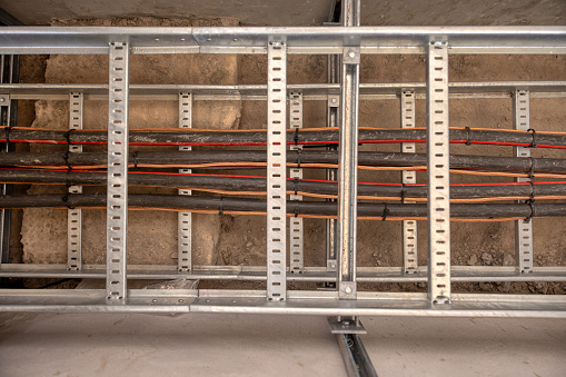 electric cable duct on a metal frame, cable pulling industrial area in a tray , industrial wiring rail , knit done, rack with electric wires, underground industrial