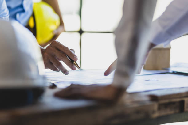 istock Brainstorming group of architects and engineers discuss building blueprint design and construction project planning on wooden table in office. 2094182640