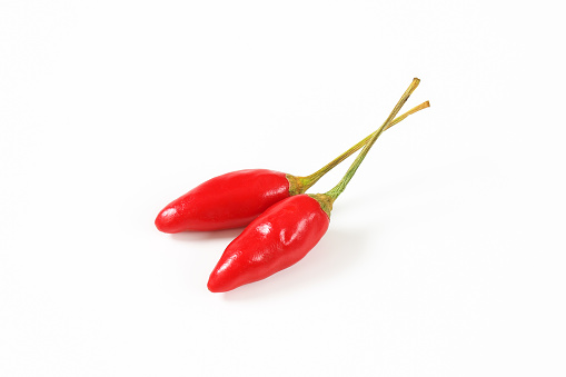 Two small red chili peppers on white background