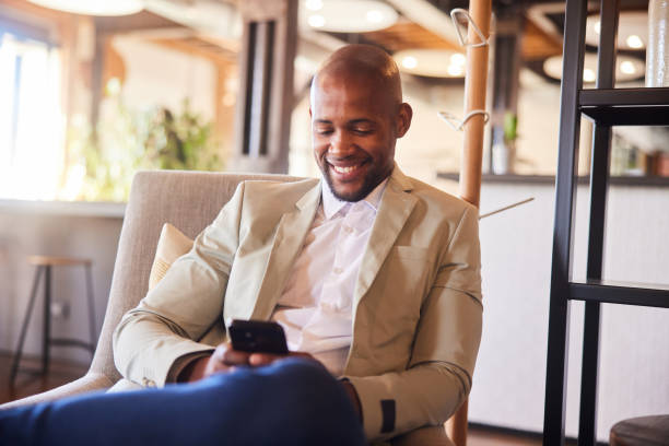 istock Smiling young businessman texting on his phone in an office lounge 2094217085