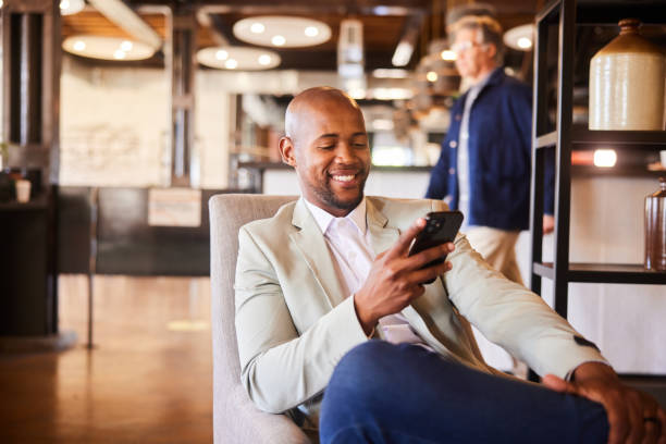 istock Young businessman smiling at a text while sitting in an office lounge 2094220784