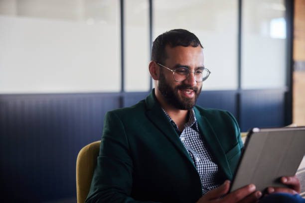 istock Smiling young businessman working on a tablet on an office sofa 2094232250
