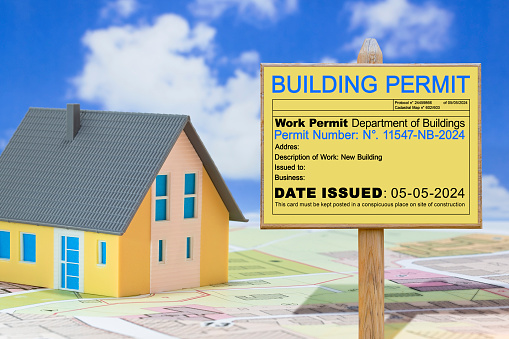 The construction industry requires adherence to laws and regulations, including obtaining a building permit, to ensure compliance in real estate projects - Concept with placard and homome model