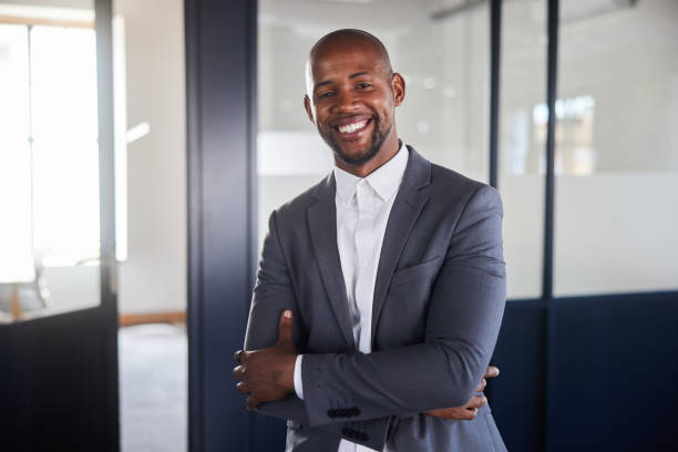 istock Young businessman smiling while standing with his arms crossed in an office 2094234881