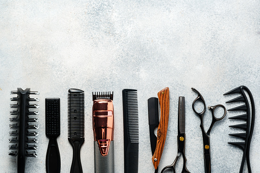 Set of hairdressing instruments on gray background close up