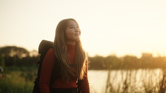 Young asian woman traveling in nature during sunset.