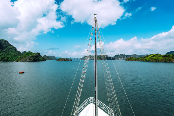A serene journey through the tranquil waters of Halong Bay, Vietnam, showcasing the bay's lush limestone cliffs from the perspective of a boat's prow.