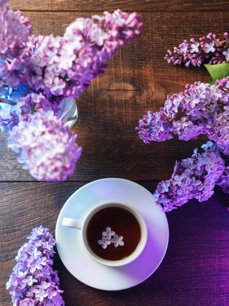 istock Tea cup on a wooden table , blooming lilac flowers . Top view 2094265086