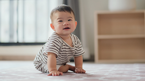 adorable baby boy crawling on the carpet floor at home snapshot of smiling happiness cosy child boy sitting on flooring in living room at home daytime