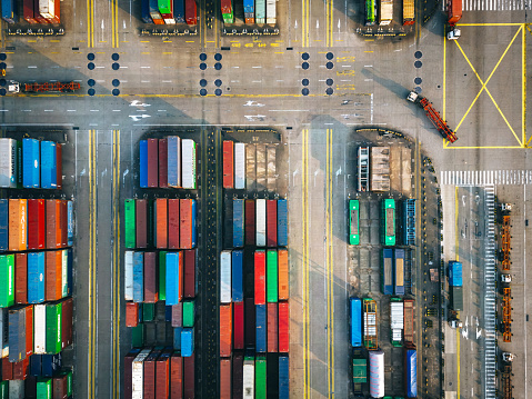 This aerial image captures the bustling Shanghai Yangshan deepwater port filled with colorful containers during a vibrant sunset.