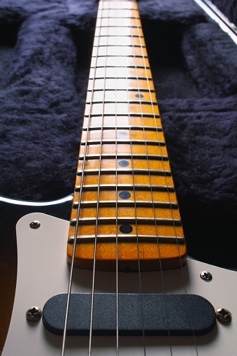 Closeup of an electric guitar's maple fretboard