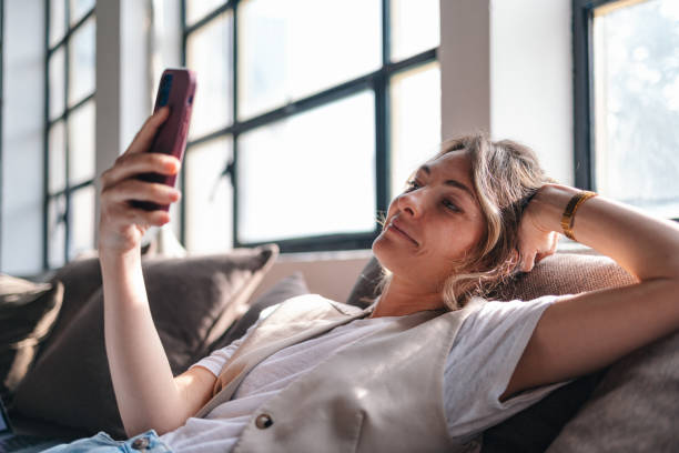 istock Young Woman Relaxing on Couch with Smartphone at Home 2094340408
