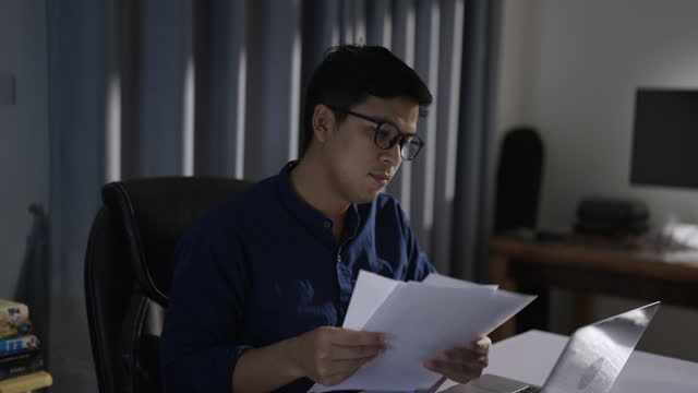 Young businessman or freelancer in eyeglass working with laptop at home office.