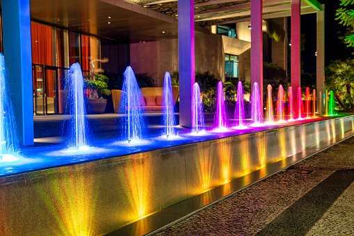 Colorful small fountains in front of a luxurious hotel at night.