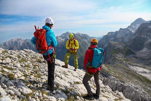 Two men and a woman on the top of the mountain and looking in their backpacks.