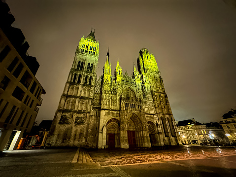 Rouen, France - 18.02.2024. Rouen Cathedral (Cathedrale de Notre-Dame) in Rouen, capital of Haute-Normandie, France. The facade of the Gothic church, it is famous for its three towers, each in a different style. Night in France, dark