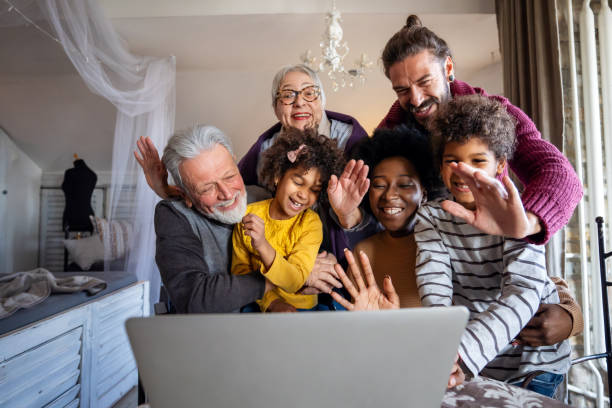 Happy multigeneration diverse family gathering around laptop and having fun during a video call