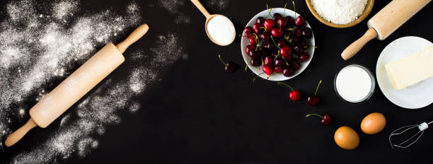Ingredients for making cherry pie or cake on the black background. Copy space. Top view.