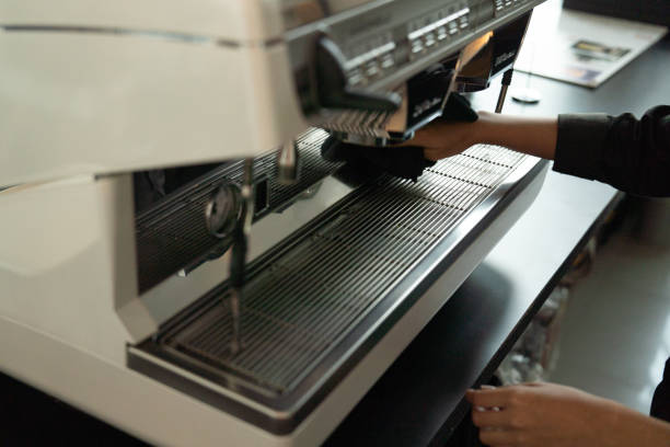 Close up on hand asian woman as barista cleaning a coffee maker after use it