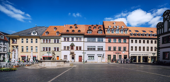 A panoramic view of historic buildings at a peaceful marketplace in Weimar, Germany on a bright sunny day with clear blue skies.