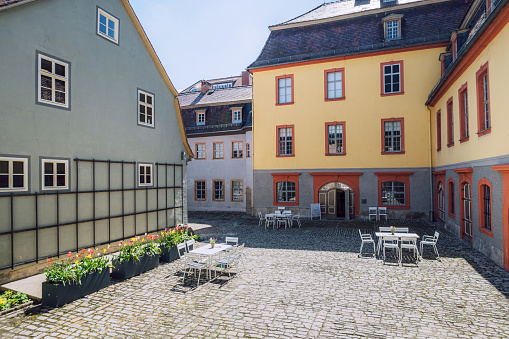 Sunny day at a quaint courtyard in Weimar, Germany, with colorful buildings, cobblestone ground, and flowers.
