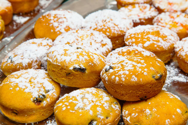 istock Ready baked muffins with raisins sprinkled with powdered sugar on a tray close-up. 2094482455
