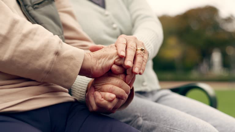 Relax, empathy and support with old couple holding hands on park bench for community, love and community. Care, retirement and nature with closeup of senior people in outdoors for collaboration
