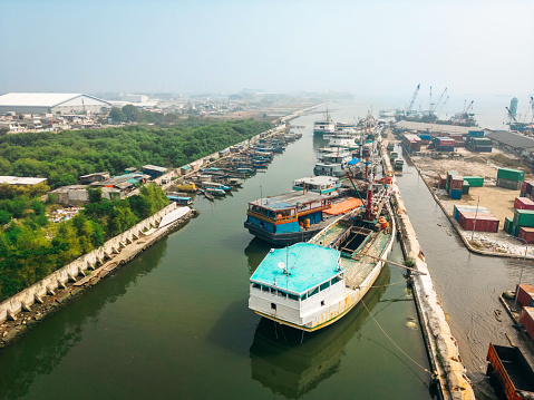 Drone shot of wooden boats moored at Sunda Kelapa, the historic port of Jakarta, Indonesia, showing vessels by the Ciliwung River estuary.