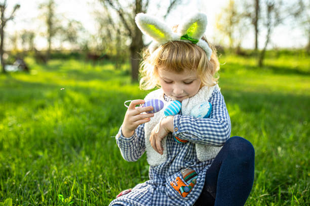 Adorable child, wearing Bunny ears, bursts with laughter amidst a blossoming garden on Easter Day, embodying the joy of springtime festivities.