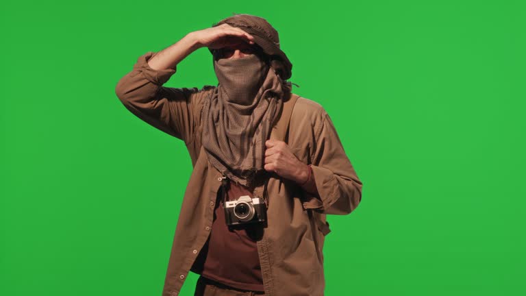 Desert Traveler in Headscarf Looking around on Green Chroma Key Wall