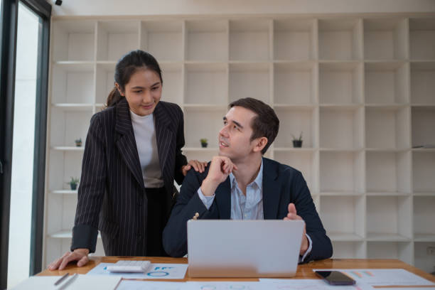 istock Two business people using a laptop in an office, a man and a women analyzing documents stat at office 2094525396