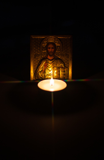 Small burning candle on icon background