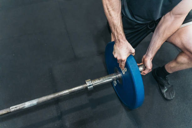 istock Unseen athlete kneeling, adjusting weight disc on barbell. 2094589137